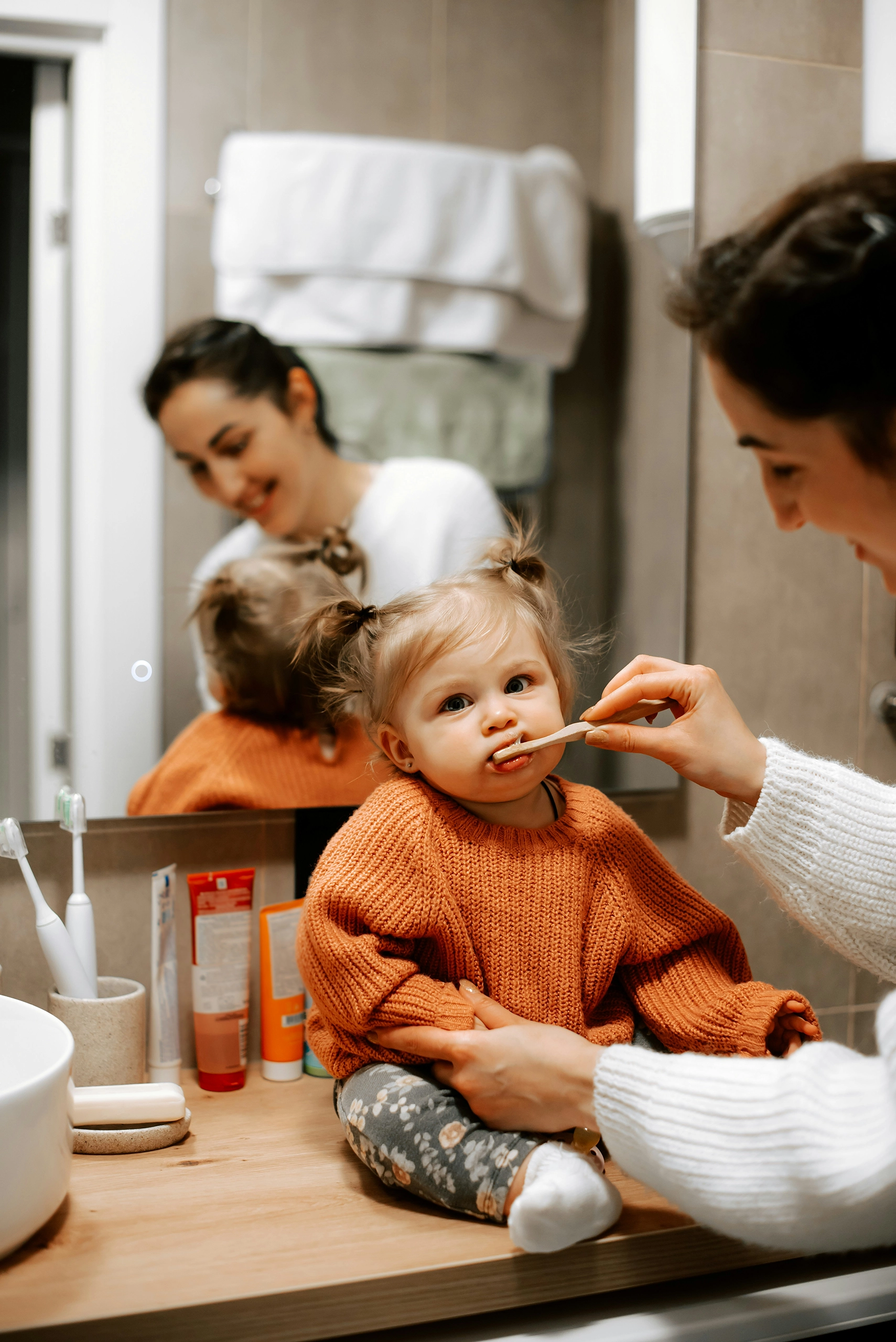 Toddler being taught how to brush her teeth