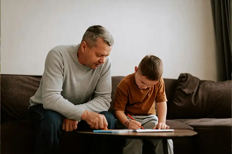 Parent helping child with autism follow a daily routine chart with visuals